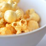 Popcorn aromatizzati con spezie e burro fuso in una ciotola colorata.