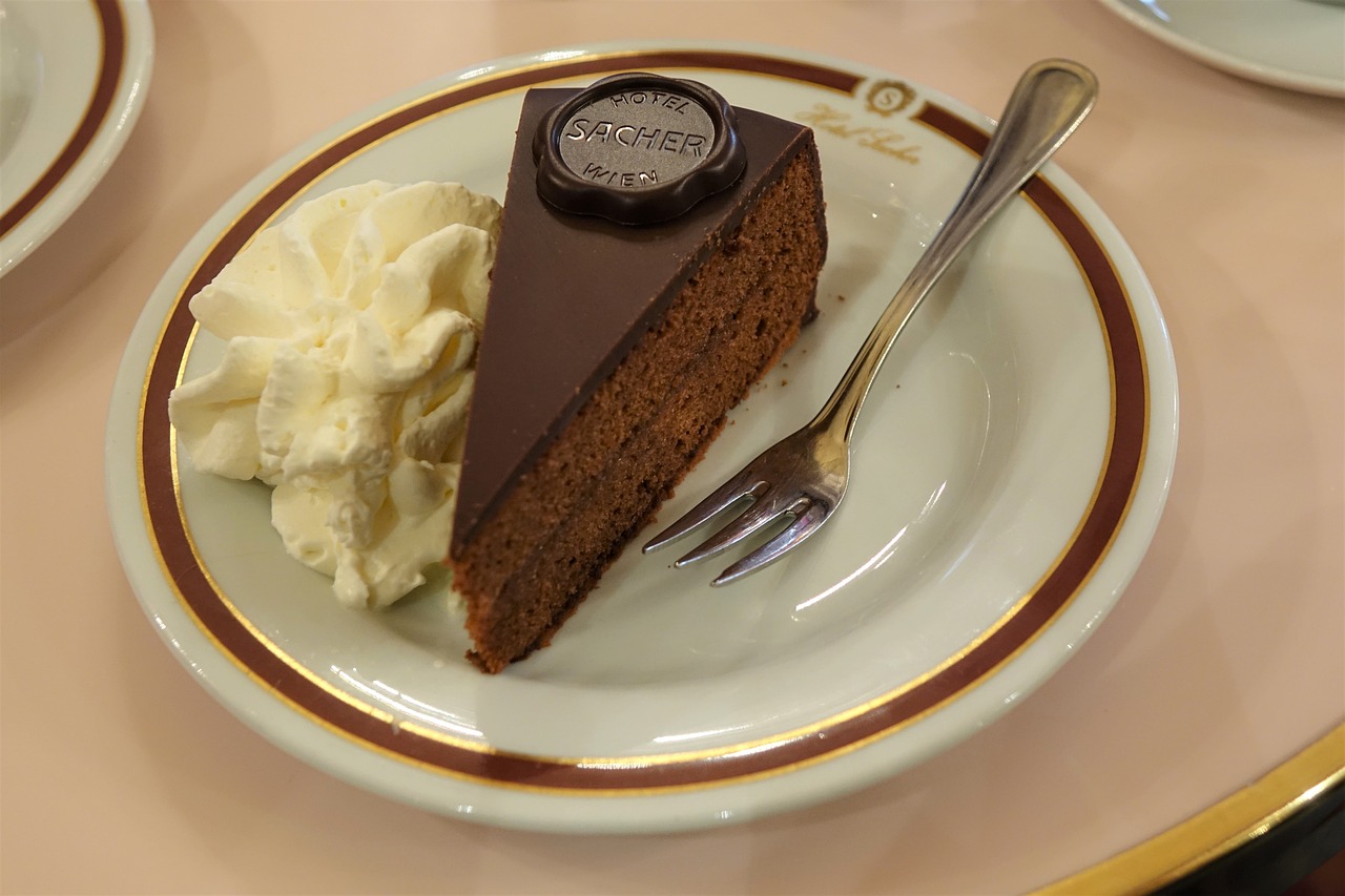 Torta Sacher con marmellata di albicocche calda spennellata in cima, su piatto decorativo.